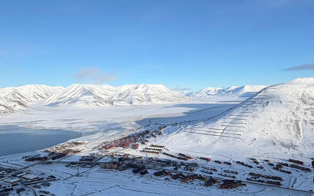 Longyearbyen spread along a snow-covered valley seen from the ridge above it