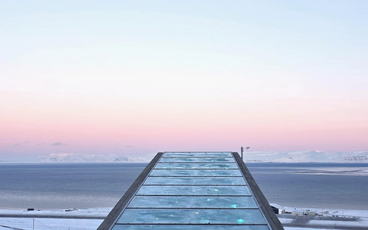 A concrete and steel entrance wedge lit against the snow of a bare mountainside