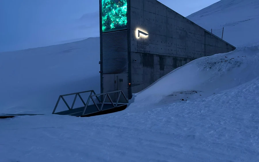 The lit concrete entrance wedge of the Global Seed Vault standing in deep snow