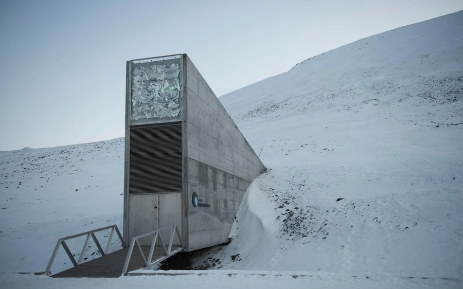 The concrete entrance of the Seed Vault on a bare snow slope under grey light